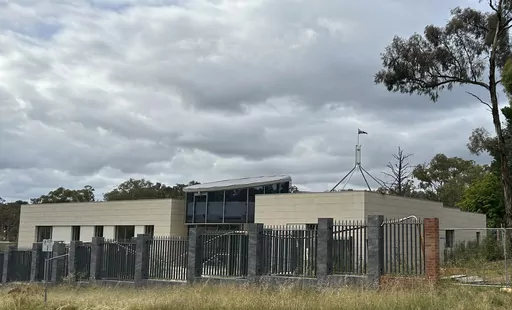 THIS CORRECTS THE PHOTOGRAPHER'S NAME TO MCGUIRK - The Australian flag flies on Parliament House, seen behind an unoccupied building on the grounds of a proposed new Russian embassy near the Australian Parliament in Canberra, Feb. 28, 2023. Australia's House of Representatives passed legislation Thursday, June 15, 2023, to prevent Russia from building a new embassy near Parliament House on security grounds. (AP Photo/Rod McGuirk)