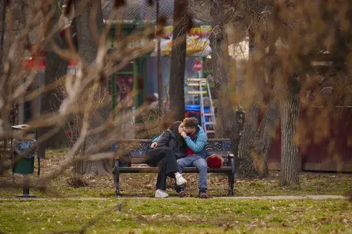A couple kiss in a park in Bucharest, Romania, Friday, Feb. 14, 2025. (AP Photo/Vadim Ghirda)