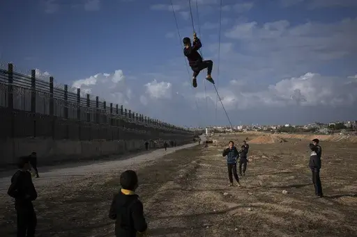 Palestinians displaced by the Israeli bombardment of the northern Gaza Strip play next to the border with Egypt, in Rafah, along the Philadelphi corridor, southern Gaza, Sunday, Jan. 14, 2024. (AP Photo/Fatima Shbair, File)
