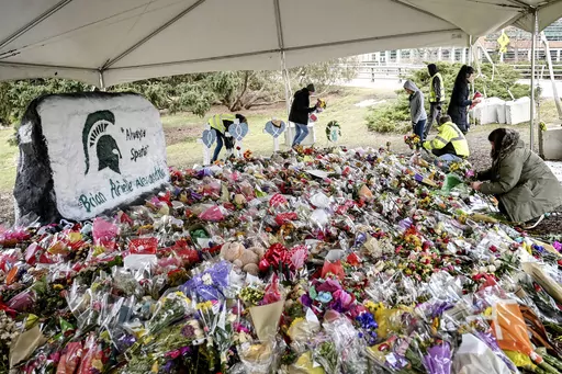 People work to remove flowers from the memorial at the Rock in honor of three students killed at Michigan State University on March 2, 2023, in East Lansing, Mich. At Michigan State, sports were suspended after gun violence on campus left three students dead. An Associated Press analysis of more than a dozen schools in the NCAA tournaments shows a wide range of policies that govern guns at those schools and uneven efforts to regulate them. (Nick King/Lansing State Journal via AP, File)
