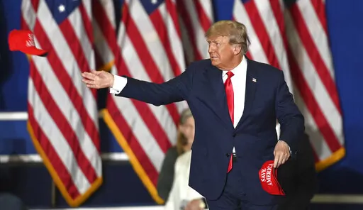 Former President Donald Trump tosses caps to the crowd as he steps onstage during a rally at the Macomb Community College Sports & Expo Center in Warren, Mich., Saturday, Oct. 1, 2022. (Todd McInturf/Detroit News via AP)