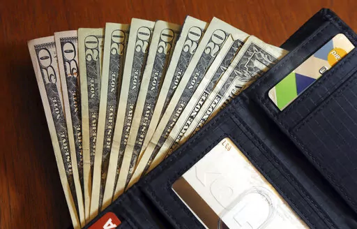 In this June 15, 2018, file photo, cash is fanned out from a wallet in North Andover, Mass. Buy now, pay later” loans typically offer a simple, zero-interest payment structure that can make keeping up with installments easy and affordable for some borrowers. But unlike other types of financing, such as credit cards, these plans aren’t currently reported to the major credit bureaus.   (AP Photo/Elise Amendola, File)