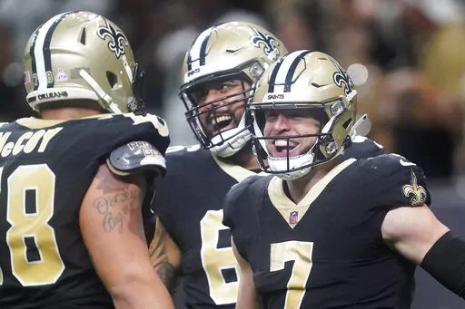 New Orleans Saints' Taysom Hill, right, celebrates his 60 yard rushing touchdown with Erik McCoy, left, and J.P. Holtz during an NFL football game against the Seattle Seahawks in New Orleans, Sunday, Oct. 9, 2022. (AP Photo/Gerald Herbert)