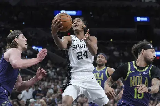 San Antonio Spurs guard Devin Vassell (24) drives to the basket against New Orleans Pelicans forward Kelly Olynyk, left, during the first half of an NBA basketball game in San Antonio, Saturday, March 15, 2025. (AP Photo/Eric Gay)
