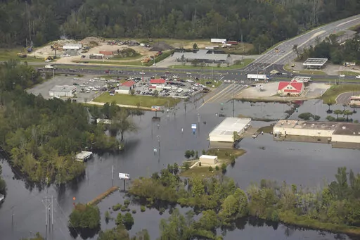 In this Monday, Sept. 24, 2018 photo, flood waters from the Neuse River cover the area a week after Hurricane Florence in Kinston, N.C. Monday Sept. 24, 2018.  Hot real estate markets have made some homeowners wary of participating in voluntary flood buyout programs, impacting efforts to move people away from flooding from rising seas, intensifying hurricanes and more frequent storms.  Flood buyout programs typically purchase flood-prone homes, raze them and turn the property into green space. (