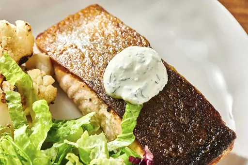 This October 2021 photo shows a recipe for crispy skinned salmon with dill sauce in New York. Pair your fish with a cool and creamy dill sauce and a couple of simple sides, and you have a restaurant-worthy meal in the comfort of home. (Cheyenne Cohen via AP)