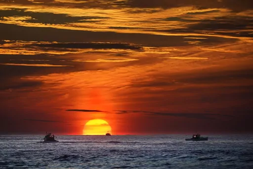 The sun rises over fishing boats in the Atlantic Ocean, Sept. 8, 2022, off of Kennebunkport, Maine. A system of ocean currents that carries heat northward across the North Atlantic could collapse during this century, according to a new study, and scientists have said before such a collapse could cause catastrophic sea-level rise and extreme weather across the globe. (AP Photo/Robert F. Bukaty, File)