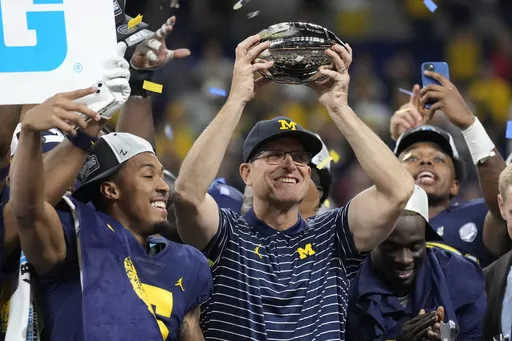 Michigan head coach Jim Harbaugh holds the trophy as he celebrates with his team after defeating Purdue in the Big Ten championship NCAA college football game, early Sunday, Dec. 4, 2022, in Indianapolis. There could be some awkward trophy ceremonies around college football's championship weekend. (AP Photo/AJ Mast, File)