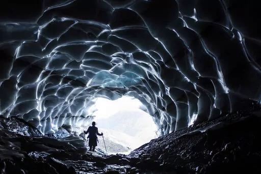 A man stands in a glacier cave at the Sardona glacier, July 27, 2022, in Vaettis, Switzerland. The melting glacier has revealed a cave. Faced with increasing demand for alpine water resources at a time of accelerating glacier melt, policymakers from 8 European countries are meeting in Switzerland to prevent a dispute over diminishing water resources from the highest peaks in the Alps. (Gian Ehrenzeller/Keystone via AP, File)
