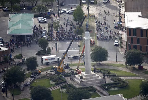 FILE -Workers prepare to take down the statue of former confederate general Robert E. Lee, which stands over 100 feet tall, in Lee Circle in New Orleans, Friday, May 19, 2017. A round patch of New Orleans green space where a larger-than-life statue of Confederate Gen.  Robert E. Lee once loomed over the landscape has officially been re-named Harmony Circle.  (AP Photo/Gerald Herbert, File)