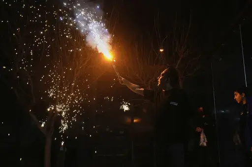 An Iranian man holds up a firework celebrating Chaharshanbe Souri, or Wednesday Feast, an ancient Festival of Fire on the eve of the last Wednesday of the Persian year, in Tehran, Iran, Tuesday, March 18, 2025. (AP Photo/Vahid Salemi)