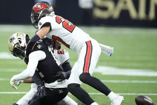 New Orleans Saints wide receiver Chris Olave, left, fumbles the ball while hit by Tampa Bay Buccaneers cornerback Zyon McCollum, top, and safety Tykee Smith, rear, that Antoine Winfield Jr. returned for a touchdown, during the first half of an NFL football game in New Orleans, Sunday, Oct. 13, 2024. (AP Photo/Michael Conroy)