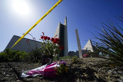 Flowers sit outside crime scene tape at Geneva Presbyterian Church on May 17, 2022, in Laguna Woods, Calif., where a shooting at the church on Sunday left one dead and five injured. Officials in California's Orange County are still trying to determine why a gunman opened fire in the church. (AP Photo/Ashley Landis, FILE)