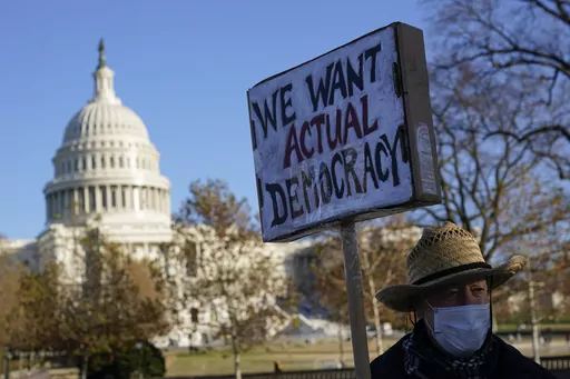 Protester David Barrows carries a sign during a rally to press Congress to pass voting rights protections and the "Build Back Better Act," Monday, Dec. 13, 2021, in Washington. A new poll finds that only about 1 in 10 U.S. adults give high ratings to the way democracy is working in the United States or how well it represents the interests of most Americans. (AP Photo/Patrick Semansky, File)