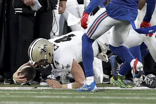 New Orleans Saints quarterback Derek Carr (4) comes down on his arm as he is tackled by the New York Giants during the fourth quarter of an NFL football game, Sunday, Dec. 8, 2024, in East Rutherford, N.J. (AP Photo/Adam Hunger)