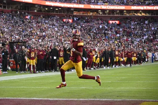 Washington Commanders quarterback Jayden Daniels (5) scores on a 2-point conversion attempt during the second half of an NFL football game against the Dallas Cowboys, Sunday, Nov. 24, 2024, in Landover, Md. (AP Photo/Nick Wass)