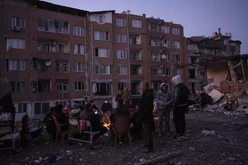 Friends and relatives of the Dagli family family gather around bonfires while rescue teams, search for family members under the rubble of a destroyed building in Antakya, southeastern Turkey, Wednesday, Feb. 15, 2023. Ever since the powerful 7.8 earthquake that has become Turkey's deadliest disaster in modern history, survivors have been gathering outside destroyed buildings, refusing to leave. (AP Photo/Bernat Armangue)