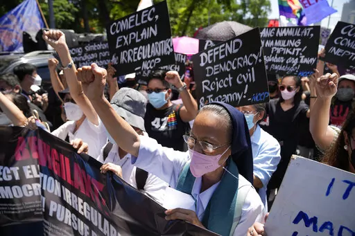 A Catholic nun clenches her fist as she joins protesters against presidential frontrunner Ferdinand "Bongbong" Marcos and running mate Sara Duterte, daughter of the current president, during a rally in Pasay, Philippines, Friday, May 13, 2022. Allies of the Philippines' presumptive next president, Marcos Jr., appear set to strongly dominate both chambers of Congress, further alarming activists after the late dictator's son scored an apparent election victory that will restore his family to the s