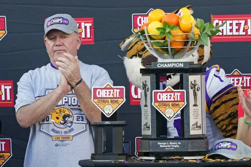 LSU head coach Brian Kelly applauds his players as he receives the championship trophy after the Citrus Bowl NCAA college football game against Purdue, Monday, Jan. 2, 2023, in Orlando, Fla. (AP Photo/John Raoux)