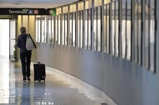 A traveler pulls their luggage between terminals at Logan International Airport, Wednesday, Jan. 11, 2023, in Boston. Travel prices are high and young Americans remain eager to vacation. Yet looming economic and personal finance trends point to trouble ahead. Millennials and Generation Z are racking up credit card debt and falling behind on payments, and many are turning to “buy now, pay later” plans to fund travel. (AP Photo/Steven Senne, File)