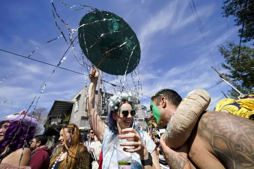 Societe de Sainte Anne parade goers march during Mardi Gras on Tuesday, March 1, 2022, in New Orleans. New Orleans is lifting its indoor mask mandate now that the annual Carnival season, which draws large crowds to city streets and packs bars and restaurants, is over, the city health director said Wednesday, March 2, 2022. (AP Photo/Gerald Herbert)