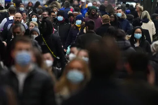 Shoppers walk down Oxford Street, Europe's busiest shopping street, in London, Dec. 23, 2021. The British government confirmed Saturday Feb. 19, 2022, that people with the coronavirus will not be legally required to self-isolate starting next week, as part of a plan for “living with COVID” that is also likely to see testing for the virus scaled back. (AP Photo/Frank Augstein, File)