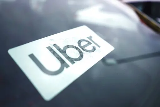 An Uber sign is displayed inside a car in Palatine, Ill., Thursday, Feb. 10, 2022. Citing record-high prices for gasoline, Uber is charging customers a new fuel fee to help offset costs for ride-hail and delivery drivers. The company announced Friday, March 11, 2022, that the temporary surcharge will be either 45 cents or 55 cents for each Uber trip and either 35 cents or 45 cents for each Uber Eats order, depending on location. (AP Photo/Nam Y. Huh, File)