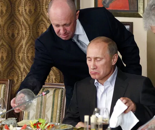 Yevgeny Prigozhin, top, serves food to then-Russian Prime Minister Vladimir Putin at Prigozhin's restaurant outside Moscow, Russia in Nov. 11, 2011. Kremlin-connected businessman Yevgeny Prigozhin kept a low profile over the years, but he has been increasingly in the spotlight recently. He has admitted that he is behind the Russian mercenary force that reportedly has been involved in conflicts around the world, including Ukraine. (AP Photo/Misha Japaridze, Pool, File)