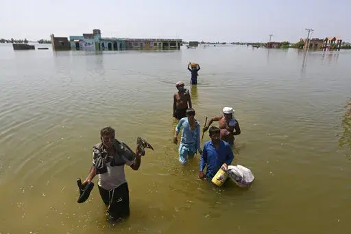 Victims of flooding from monsoon rains carry belongings salvaged from their flooded home in the Dadu district of Sindh Province, of Pakistan, Sept. 9, 2022. Ten years ago scientists warned the world about how climate change would amplify extreme weather disasters. There are now deadly floods, oppressive heat waves, killer storms, devastating droughts and what scientists call unprecedented extremes as predicted in 2012. (AP Photo/Fareed Khan, File)