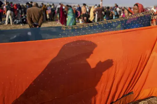 The shadow of a pilgrim falls on a sari held up to dry at the confluence of the Ganges, the Yamuna and the mythical Saraswati rivers during Maha Kumbh festival, in Prayagraj Friday, Feb. 7, 2025. (AP Photo/Rajesh Kumar Singh)