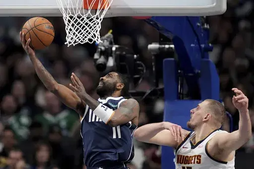 Dallas Mavericks guard Kyrie Irving (11) goes up for a shot as Denver Nuggets' Nikola Jokic, right, defends in the second half of an NBA basketball game in Dallas, Tuesday, Jan. 14, 2025. (AP Photo/Tony Gutierrez)