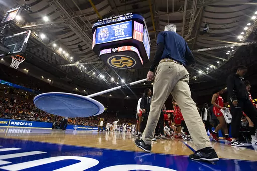 An arena crew member prepares to wipe the floor in the first half of an NCAA college basketball game between LSU and Georgia during the Southeastern Conference women's tournament in Greenville, S.C., Friday, March 3, 2023. The games was delayed due to excessive high winds causing a damper to open in an exhaust fan in the roof, allowing water to enter the roof and fall to the court. The game was delayed until the severe weather passed. (AP Photo/Mic Smith)