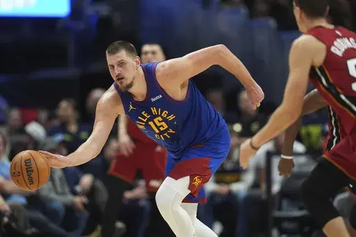 Denver Nuggets center Nikola Jokic, left, collects a loose ball as Miami Heat forward Duncan Robinson defends in the second half of an NBA basketball game Friday, Nov. 8, 2024, in Denver. (AP Photo/David Zalubowski)