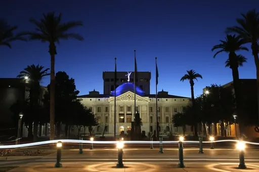 The blur of car lights zip past the Arizona Capitol as the dome is illuminated on April 15, 2020, in Phoenix. Social media users are falsely suggesting Arizona lawmakers have brought criminal charges against the state’s sitting governor. But no such indictment has been issued, and the state legislature isn’t authorized to issue such formal accusations of criminal wrongdoing in the first place. (AP Photo/Ross D. Franklin, File)
