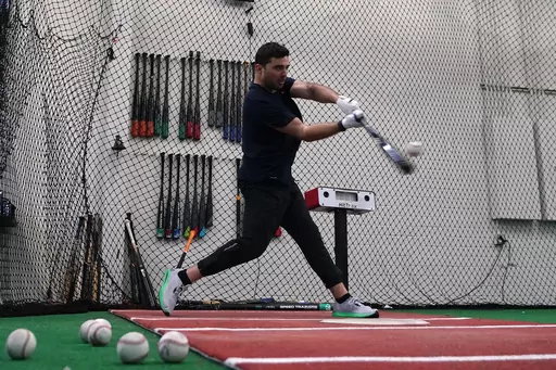 A batter takes a swing inside a batting cage at the Driveline facility in Scottsdale, Ariz., Thursday, Feb. 16, 2023. The batting information is read by a sensor device just to the right of the batter and the information is projected onto the screen in a different part of the cage area. (AP Photo/Ross D. Franklin)