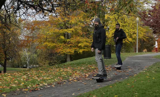 Two people ride Onewheels through Wright Park in Tacoma, Wash., on Oct. 26, 2018. All models of Onewheel self-balancing electric skateboards are under recall after at least four deaths and multiple injuries were reported in recent years, federal regulators said last week.(AP Photo/Ted S. Warren, File)