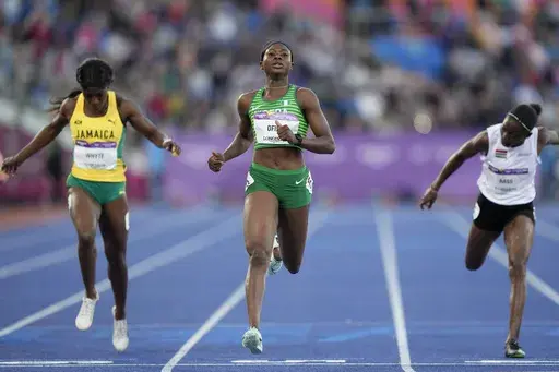 Favour Ofili of Nigeria, center crosses the finish line ahed of Natalliah Whyte of Jamaica, left, and Gina Bass of The Gambia, right, in a Women's 200 meters semifinal during the athletics competition in the Alexander Stadium at the Commonwealth Games in Birmingham, England, Friday, Aug. 5, 2022. Nigeria's national champion in the women's 100-meter sprint won't run the race at the Olympics because she says her country's track federation didn't enter her into the field in time. (AP Photo/Manish S