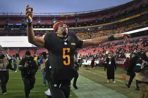 Washington Commanders quarterback Jayden Daniels (5) celebrates the team's 42-19 win against the Tennessee Titans in an NFL football game Sunday, Dec. 1, 2024, in Landover, Md.(AP Photo/Steve Ruark)
