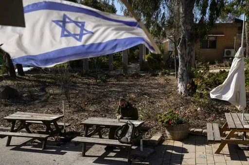 An Israeli soldier sits at a table inside the Bahat winery in the kibbutz of Ein Zivan in the Israeli-annexed Golan Heights, which most of the world considers occupied Syrian territory, Thursday, Dec. 19, 2024. (AP Photo/Matias Delacroix)