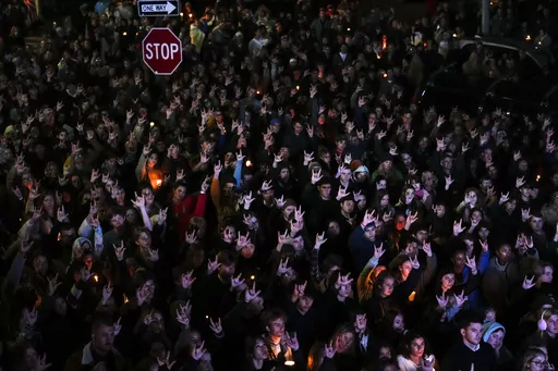 People sign "I love you," while gathered at a vigil for the victims of mass shootings days earlier, Sunday, Oct. 29, 2023, outside the Basilica of Saints Peter and Paul in Lewiston, Maine. Two senators from Maine are asking the U.S. Army inspector general to provide a full accounting of interactions with a reservist before he killed multiple people at a bowling alley and bar. (AP Photo/Matt Rourke, File)