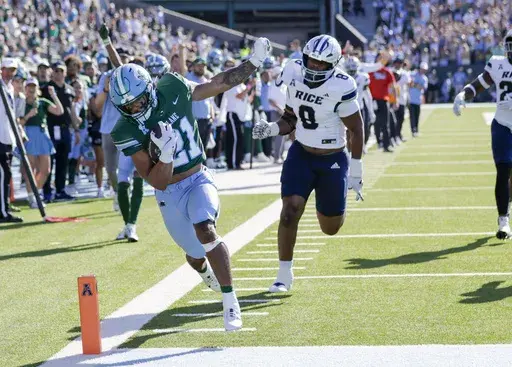Tulane running back Makhi Hughes (21) scores on a 29-yard pass from quarterback Darian Mensah (10) as Rice defensive lineman Joseph Mutombo (8) gives chase during the first half of an NCAA football game at Yulman Stadium in New Orleans, Saturday, Oct. 19, 2024. (Scott Threlkeld/The Times-Picayune/The New Orleans Advocate via AP)
