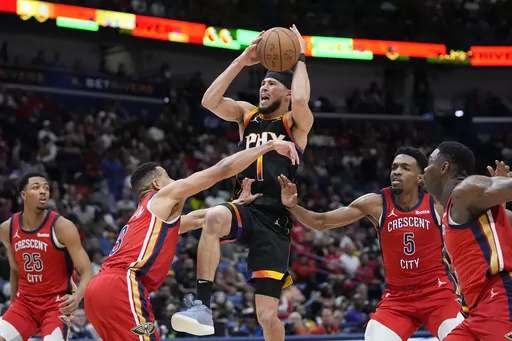 Phoenix Suns guard Devin Booker (1) goes to the basket between New Orleans Pelicans guard CJ McCollum (3) and forward Herbert Jones (5) in the second half of an NBA basketball game in New Orleans, Monday, April 1, 2024. The Suns won 124-111. (AP Photo/Gerald Herbert)