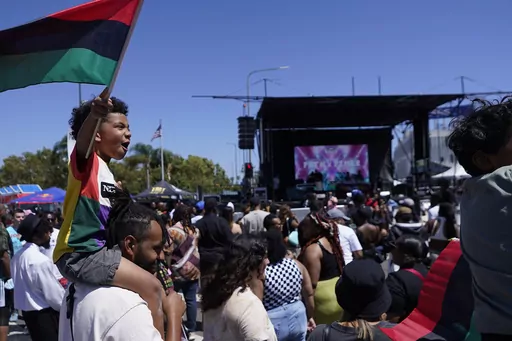 Julien James carries his son, Maison, 4, holding a Pan-African flag, to celebrate during a Juneteenth commemoration at Leimert Park in Los Angeles on June 18, 2022. Since it was designated a federal holiday in 2021, Juneteenth has become more universally recognized beyond Black America. For over one-and-a-half centuries, the Juneteenth holiday has been sacred to many Black communities. (AP Photo/Damian Dovarganes, File)
