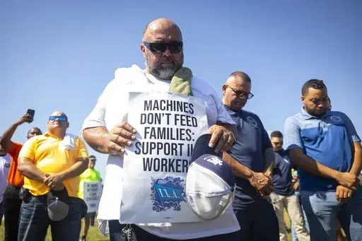 Longshoremen bow for a prayer during a strike at the Bayport Container Terminal on Tuesday, Oct. 1, 2024, in Houston. (AP Photo/Annie Mulligan)