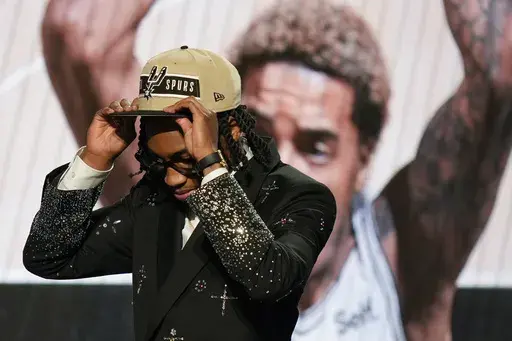 Rob Dillingham, right, dons a San Antonio Spurs hat after being selected by the Spurs during the first round of the NBA basketball draft, Wednesday, June 26, 2024, in New York. (AP Photo/Julia Nikhinson)