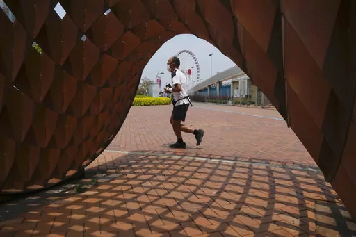 A man jogs in a park in Hong Kong, Thursday , May 5, 2022. Hong Kong on Thursday reopened beaches and pools in a relaxation of COVID-19 restrictions, while China's capital Beijing began easing quarantine rules for arrivals from overseas. (AP Photo/Kin Cheung)