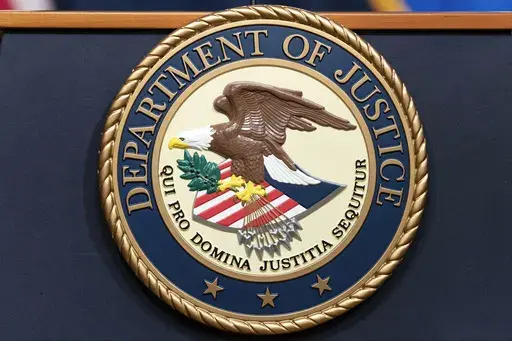 The Department of Justice seal is seen during a news conference at the DOJ office in Washington, May 16, 2023. A Florida attorney has pleaded guilty to using a rifle to try to detonate explosives outside the Chinese embassy in 2023, in Washington, D.C. Christopher Rodriguez also pleaded guilty on Friday, Aug. 2, 2024, to bombing a sculpture of communist leaders Vladimir Lenin and Mao Zedong in a courtyard outside a building in San Antonio, Texas, in 2022. (AP Photo/Jose Luis Magana, File)