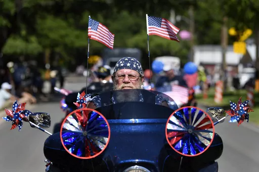 Flags and patriotic stars flutter and twirl as Dwane Tervooren rides with other motorcyclists during Tuesday's Independence Dayparade in Buffalo Gap, Texas Tuesday, July 4, 2023. (Ronald W. Erdrich /The Abilene Reporter-News via AP)
