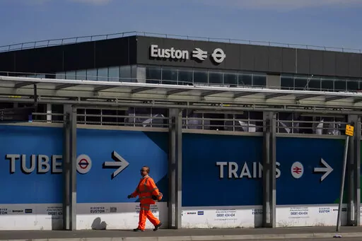 A construction worker walks past Euston station, in London, Tuesday, June 21, 2022. Tens of thousands of railway workers walked off the job in Britain on Tuesday, bringing the train network to a crawl in the country’s biggest transit strike for three decades. (AP Photo/Alberto Pezzali)