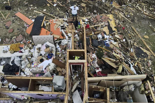A man, top center, salvages a jacket as he looks over a tornado damaged home, March 26, 2023, in Rolling Fork, Miss. An unusual weather pattern has set in, triggering the devastating tornado that hit Rolling Fork, and meteorologists fear this Friday, March 31, will be one of the worst days, with much more to come. (AP Photo/Julio Cortez, File)